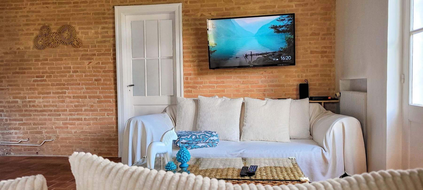 Salon télévision canapé blanc mur brique