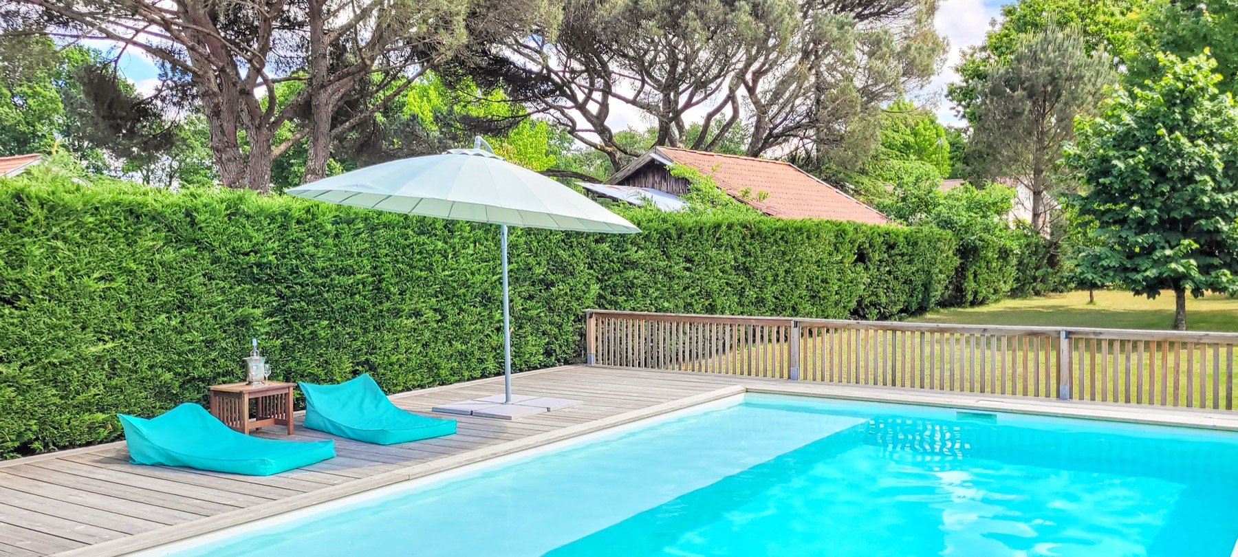 Piscine poufs turquoise parasol terrasse bois